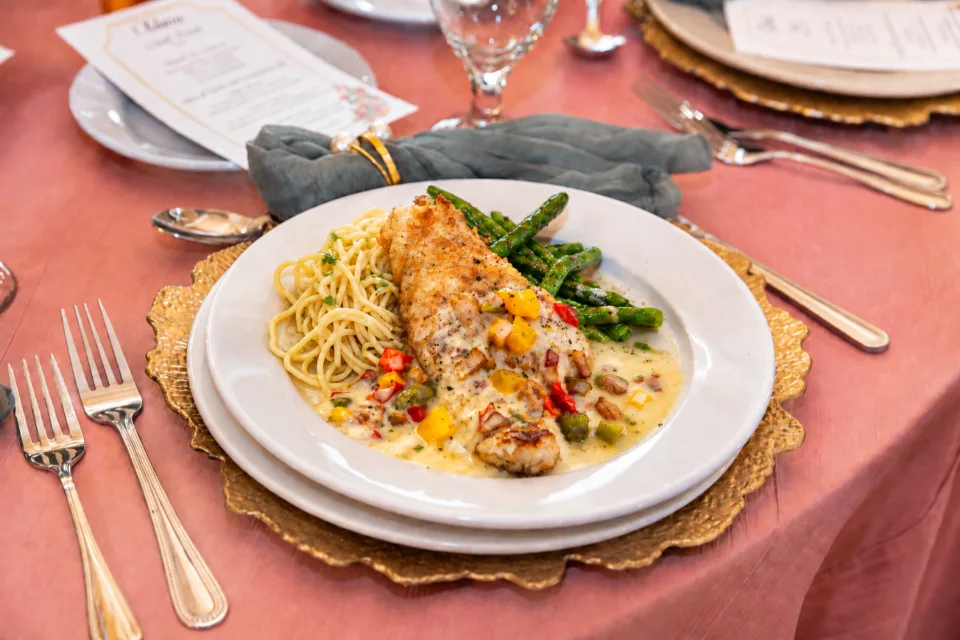 Plated entrée with pasta and asparagus at a reception table