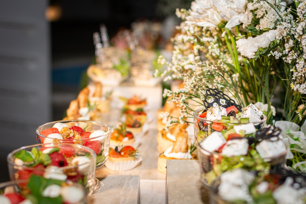 A buffet of individual party dishes on a table covered in flowers