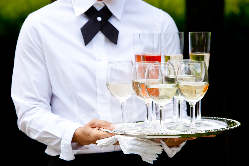 A waiter in a white shirt carrying a platter with drinks